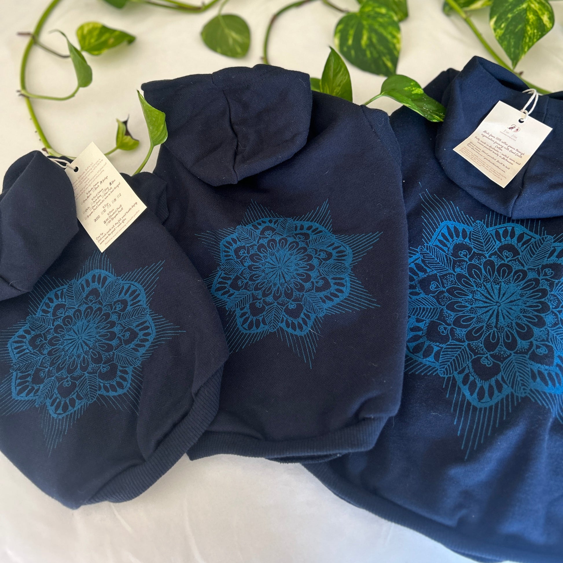 Three sizes of mandala indigo dog hoodies laid flat showing size variance